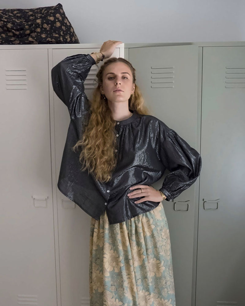 Blouse bohème noire à fils lurex et manches bouffantes, portée avec une jupe longue fleurie turquoise et crème